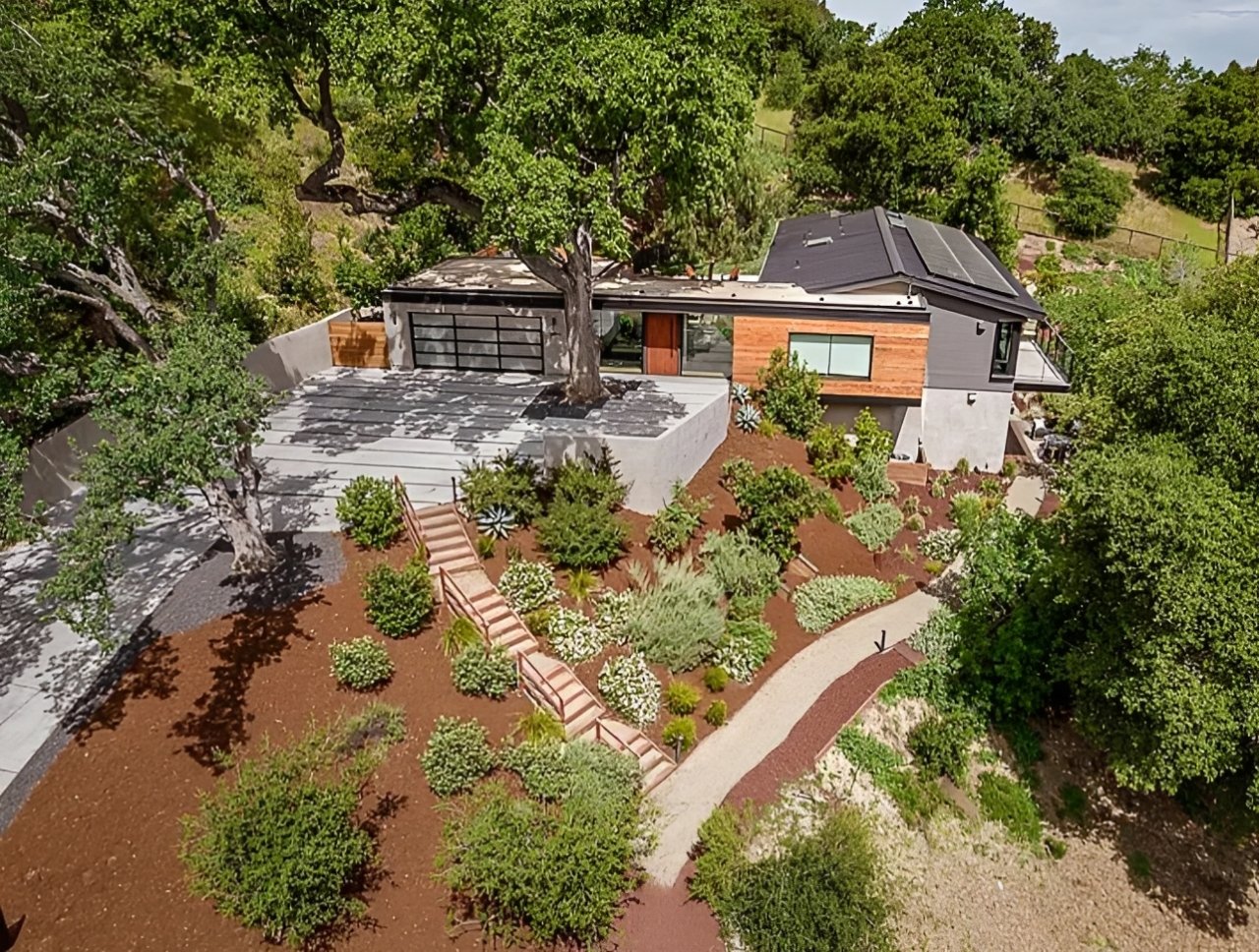Aerial view of a modern hillside home with landscaped garden